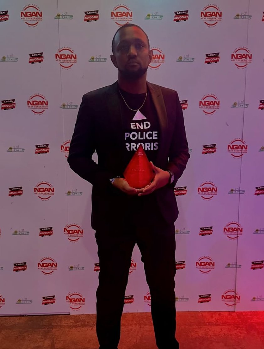 Chas Moore in a black blazer holding a red pyramid award at the NGAN Gala